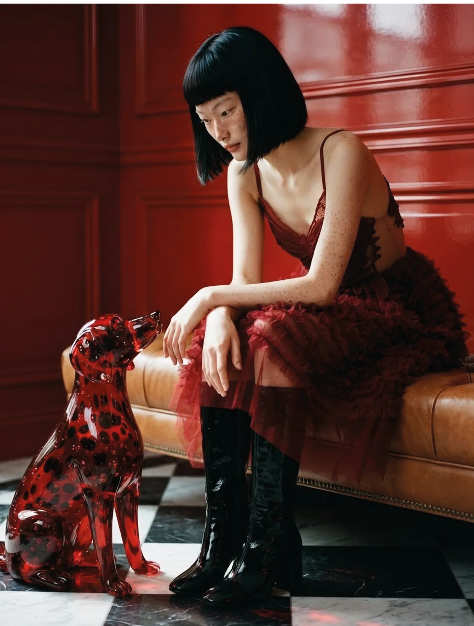 Aylin in the red ruffled dress on a leather sofa