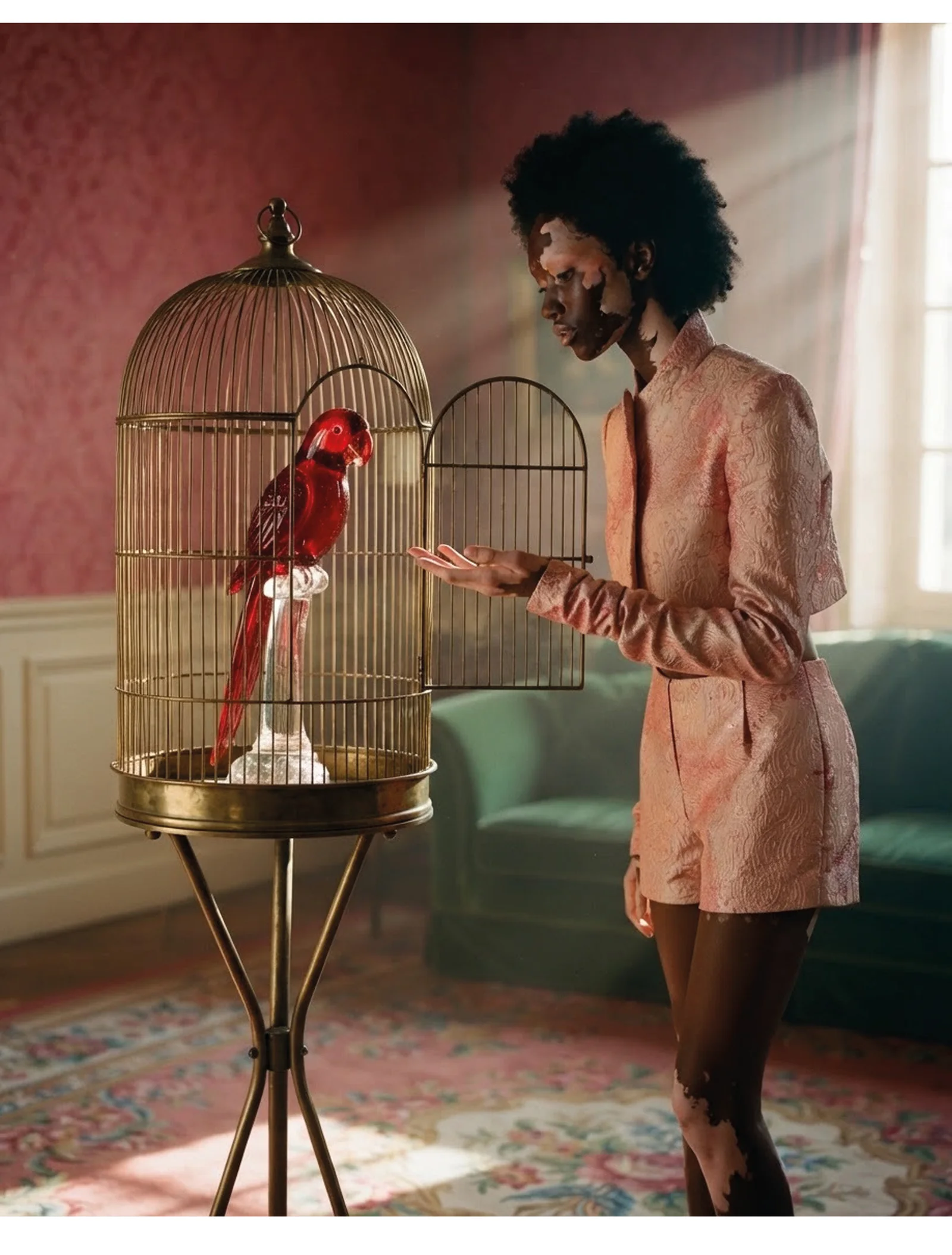 Naima wearing the same brocade set beside a birdcage