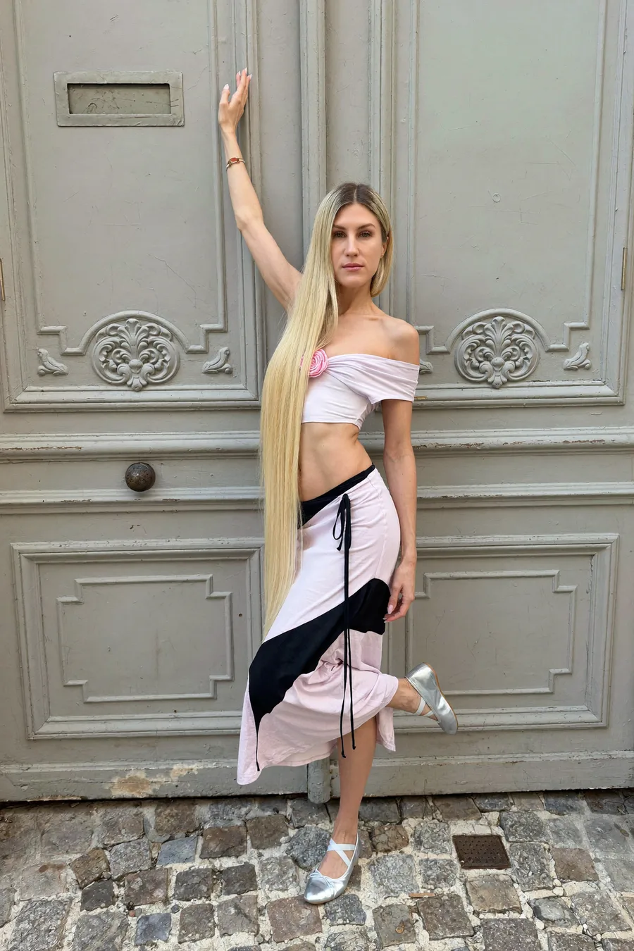 Full-body shot in a ballet pose in front of a pale grey Parisian door &mdash; AI-generated