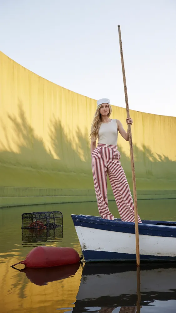 Woman in a boat by a yellow wall, cinematic — AI · The o.KI Agency