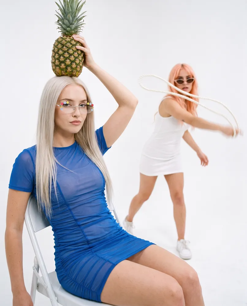 Two women with pineapple, creative editorial — AI · The o.KI Agency